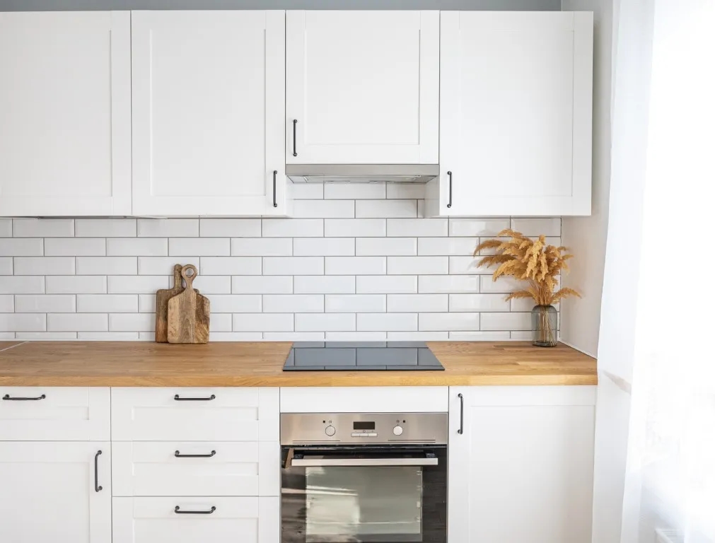 Jakie materiały wybrać między szafkami w białej kuchni z drewnianym blatem